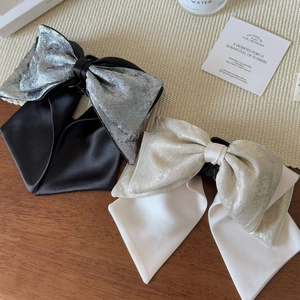 Detail of premium double-layered satin bow hair claw clip with contrast metallic texture