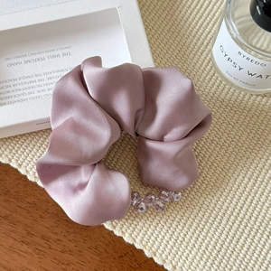 Detailed close-up of a satin scrunchie with crystal beads on a refined aesthetic tabletop