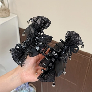 Détail de la pince à cheveux avec nœud en dentelle noire et pendentifs en cristal