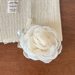 Détail de la pince à cheveux fleur en maille blanche avec perle et nœud en ruban