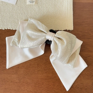 Detail view of the multi-layered satin bow hair clip with champagne pearl shimmer coating