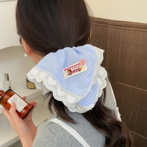 Chouchou en dentelle à rayures bleues avec détail de bouton porté sur de longs cheveux sombres