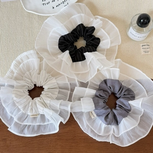 Detailed macro of layered organza scrunchies with handmade labels on wooden surface