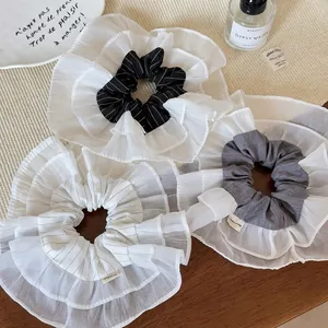 Three-piece set of oversized layered mesh scrunchies with handmade labels in soft neutral tones