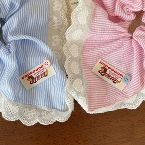 Détail de chouchous à rayures roses et bleues avec dentelle brodée sur fond en bois