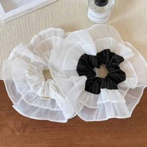 Close-up of oversized ruffled tulle scrunchies in black and white with Hand Made label