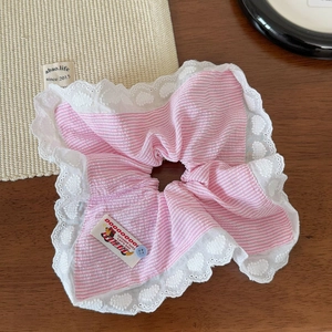 Détail de chouchou à rayures roses avec dentelle et patch chiot sur table en bois