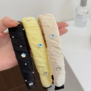 Détail de serre-têtes en satin avec perles et cristaux en noir, jaune et crème