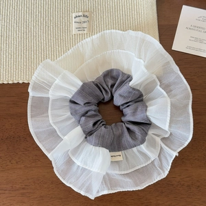 Detail of layered white organza and grey pinstripe fabric scrunchie with handmade label