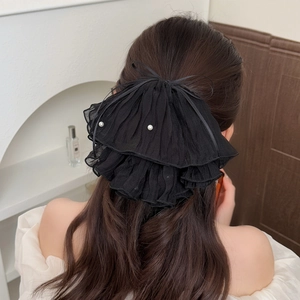 Elegant black pleated ribbon bow hair claw with pearls shown on model's hairstyle