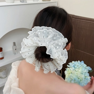 Elegant white lace scrunchie with black polka dots on a stylish bun hairstyle