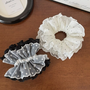 Detail showing layered white mesh and black polka dot pleated scrunchie fabric texture
