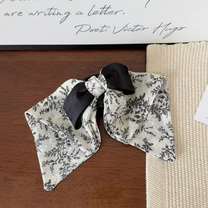 Detail of elegant dual-layer bow hair clip with floral print and black satin ribbon