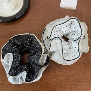 Detail of black and white polka dot scrunchies with delicate lace edges on a wooden table