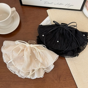 Detailed view of elegant bow hair claws with lace, pearls, and ribbon on a vintage table