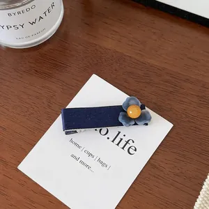 Détail de la pince à cheveux fleur en satin bleu foncé avec perle ambrée