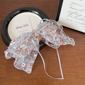 Détail de la pince à cheveux en seersucker floral avec perles et bordure bleu clair