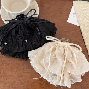 Elegant ribbon lace and pearl hair claws in black and cream on a wooden desk