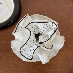 Detail of a large dot lace scrunchie made of light chiffon on a wooden desk