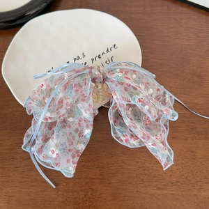 Détail de la pince à cheveux avec nœud floral, perles blanches et tissu rose
