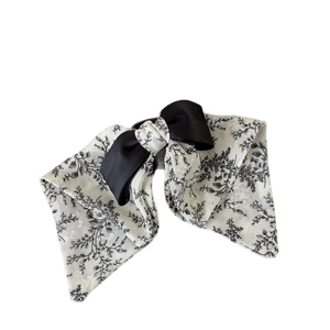 Elegant bow hair claw with floral print and black ribbon on a white background