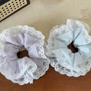 Détail de chouchous bleu clair et violet avec bordure en dentelle et tissu à pois translucide