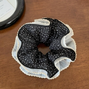 Detailed macro view of black polka dot layered mesh scrunchie on a wooden surface
