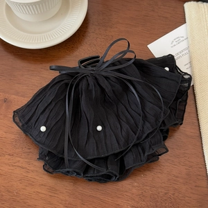 Detailed shot of black pleated chiffon hair claw clip with pearls and ribbon bow decoration