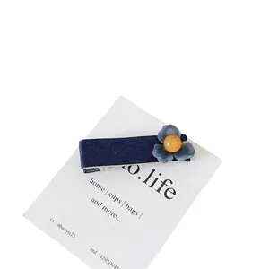 Barrette en satin bleu marine avec fleur bleu-violet et perle orange sur carte