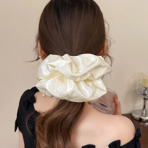 Close-up of elegant ivory satin camellia flower scrunchie on a ponytail