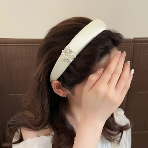 Serre-tête large en satin crème avec perles et strass porté par un mannequin élégant