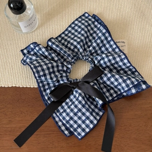 Detail of blue and white checkered fabric hair scrunchie with a black satin bow