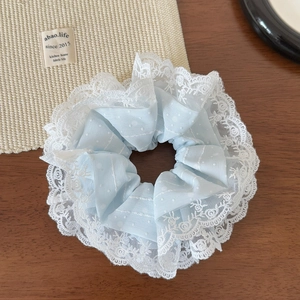 Détail d'un chouchou en tulle bleu clair avec dentelle sur un bureau en bois rustique