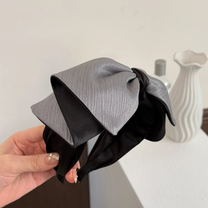 Détail d'un serre-tête en satin gris et noir avec texture métallique et large structure