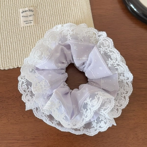 Détail d'un chouchou violet clair à pois avec une bordure délicate en dentelle blanche