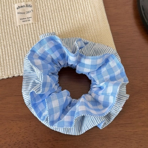 Detail of light blue checkered and striped fabric scrunchie with elastic texture