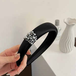 Détail du serre-tête en satin noir avec perles grises et strass sur le côté