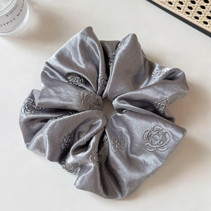 Detail of silver grey satin scrunchie featuring elegant rose floral embroidery