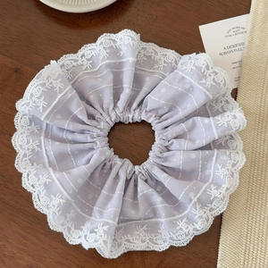 Detail of a lavender lace oversized scrunchie with polka dots on a dark wood background