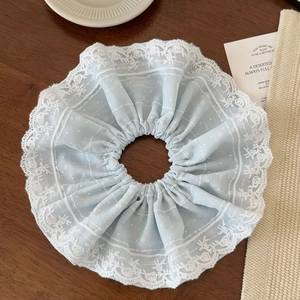 Detail of light blue lace scrunchie with floral embroidery and polka dot patterns