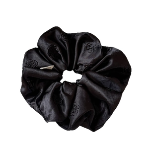Elegant black satin scrunchie with detailed rose embroidery and white fabric tag