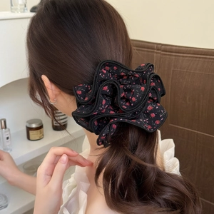 Floral scrunchie with red rose print on black fabric featuring layered ruffle edges