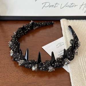 Detail of black gold polka dot headband with crystals and spikes on textured background