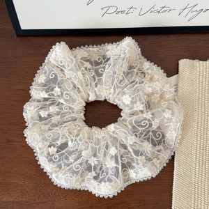 Detailed macro view of ivory lace scrunchie with floral embroidery and delicate bead trim