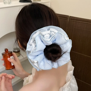 Chouchou en dentelle bleue et blanche sur une coiffure pour un style doux et élégant