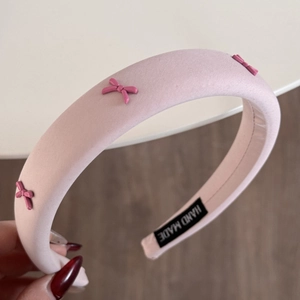 Roze gevoerde hoofdband met kleine strikjes en handgemaakt label voor een elegant kapsel