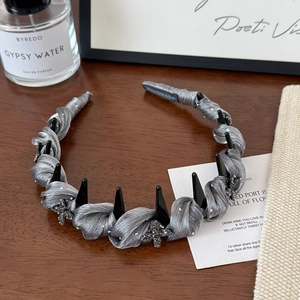 Detail view of handmade grey mesh headband with black spikes and cross crystal embellishments