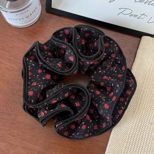 Macro shot of tiered black hair scrunchie with red floral print and elegant ruffles