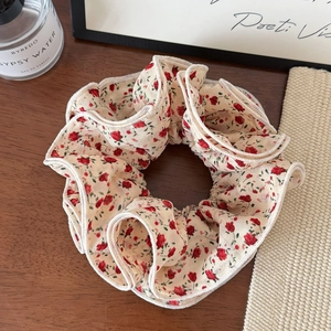 Detailed close-up of ivory floral scrunchie with red rose print and pleated edges