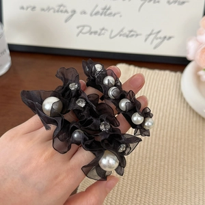 Elegant black lace hair scrunchies with faux pearls and rhinestones on a warm background